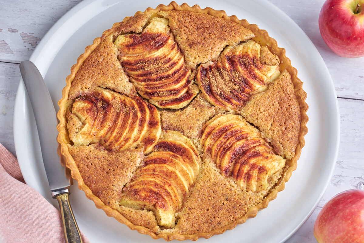 Platte mit Apfeltarte mit Frangipane, garniert mit Äpfeln und Zimt auf der Oberseite